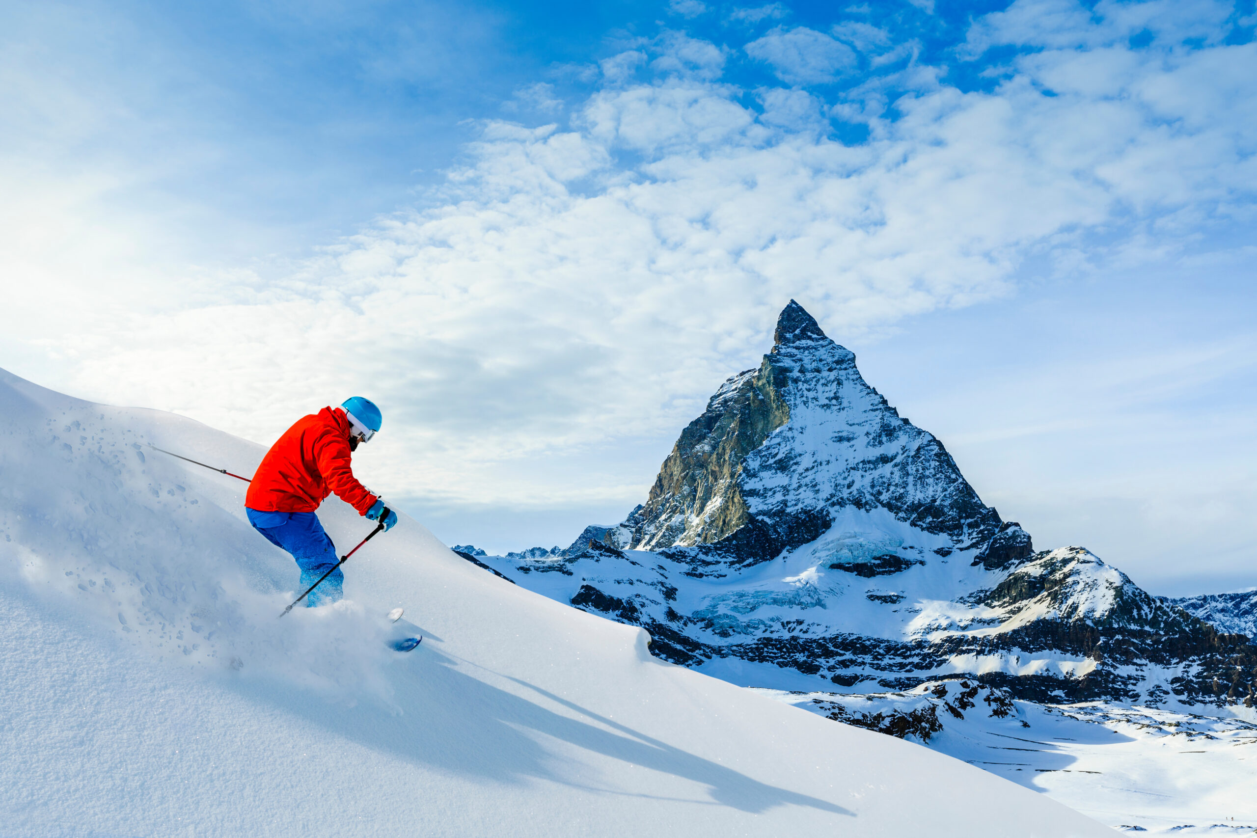 Man skiing on fresh powder snow with Matterhorn in background, Zermatt in Swiss Alps.